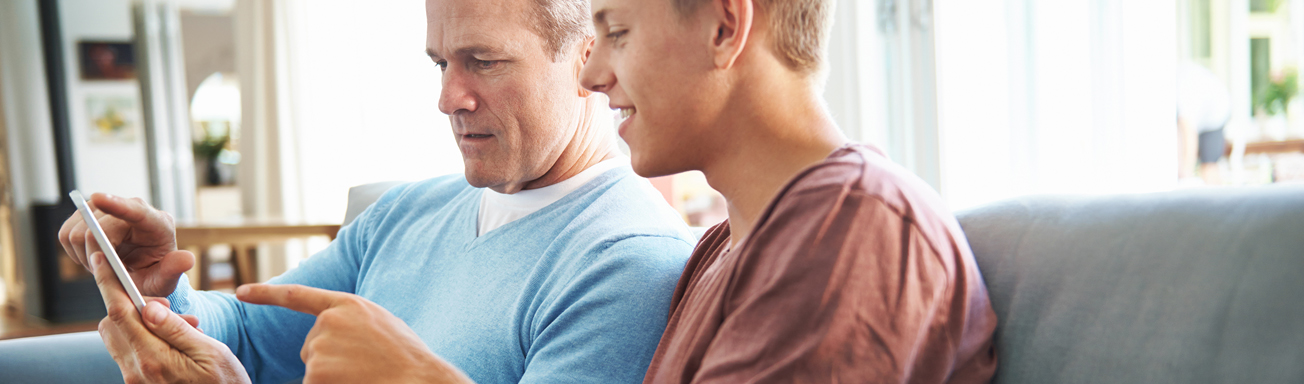 Teenage boy and father using smart phones