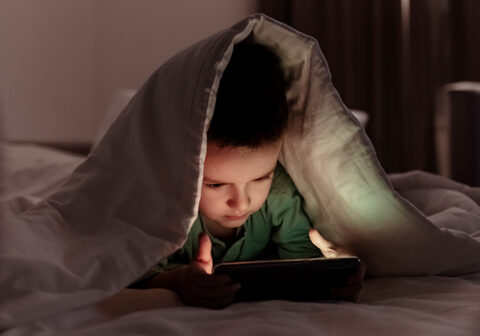boy playing with tablet in bed