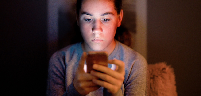 A teen victim of sextortion looking at phone